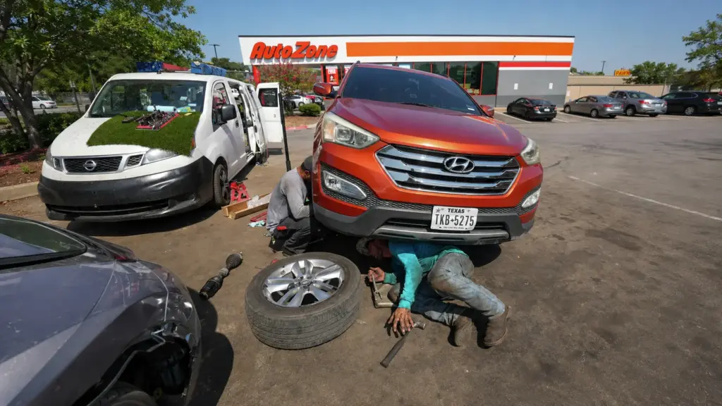 Fim das oficinas? Estacionamento de loja de autopeças vira ponto de trabalho para dezenas de mecânicos, que consertam carros ao ar livre e criam uma alternativa informal às garagens tradicionais