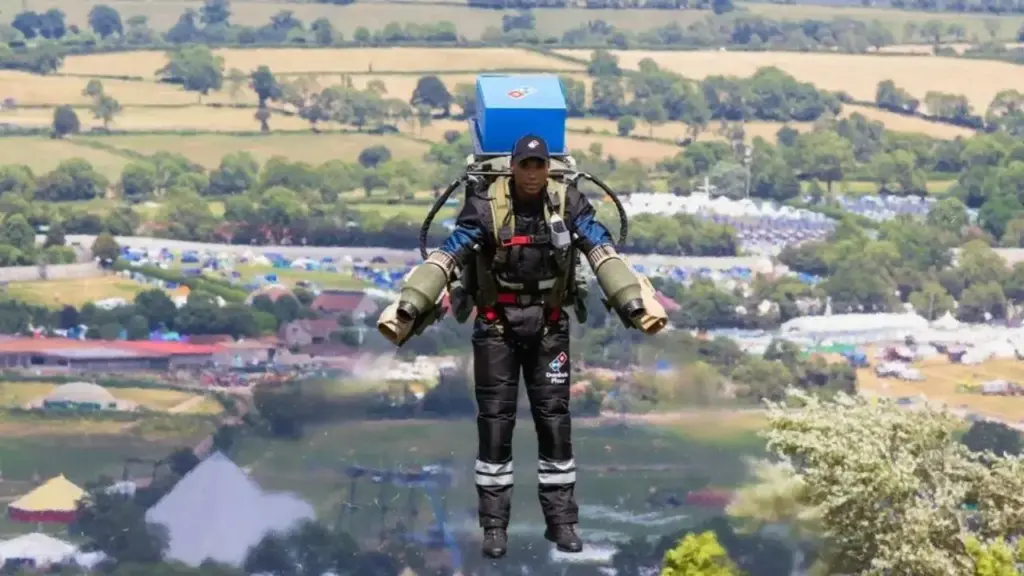 Entregador veste jetpack e literalmente voa com pizzas até clientes no Festival de Glastonbury, no Reino Unido, enquanto a Domino’s usa traje a jato desenvolvido pela Gravity Industries para enfrentar a alta demanda de um evento que reúne mais de 200 mil pessoas e transforma o delivery em atração tecnológica Entregador veste jetpack e literalmente voa com pizzas até clientes no Festival de Glastonbury, no Reino Unido, enquanto a Domino’s usa traje a jato desenvolvido pela Gravity Industries para enfrentar a alta demanda de um evento que reúne mais de 200 mil pessoas e transforma o delivery em atração tecnológica
