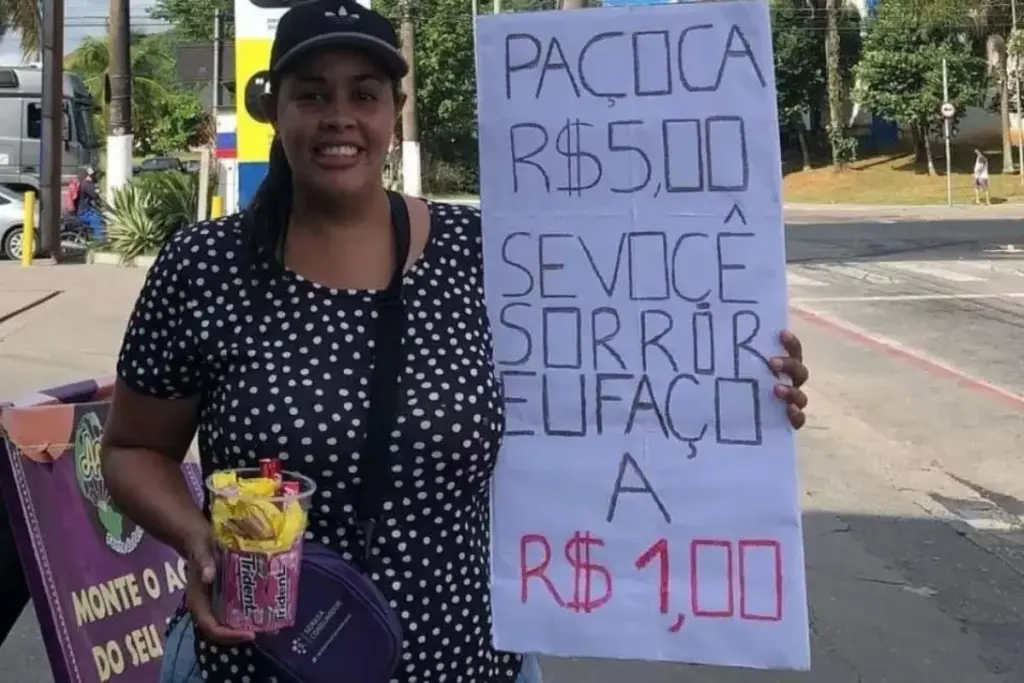 Vendedora chama a atenção num semáforo de Guarujá ao anunciar a paçoca de R$ 5 por R$ 1 para quem sorrir, motoristas percebem a estratégia da simpatia contra o aperto e transformam a vendedora em fenômeno de vendas e doações Vendedora chama a atenção num semáforo de Guarujá ao anunciar a paçoca de R$ 5 por R$ 1 para quem sorrir, motoristas percebem a estratégia da simpatia contra o aperto e transformam a vendedora em fenômeno de vendas e doações