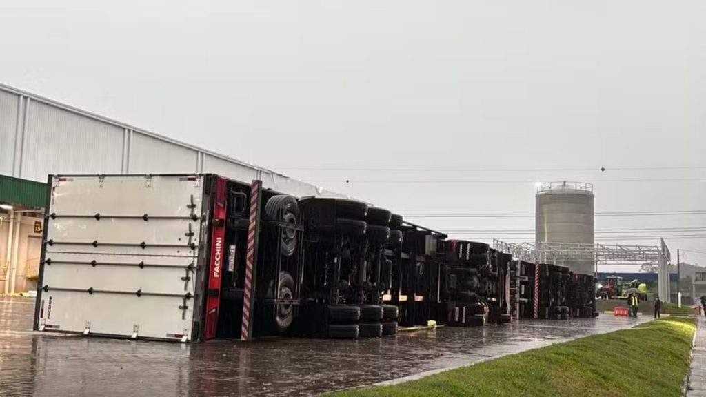 Ventania derruba pelo menos três carretas em centro de distribuição no RS, incluindo veículo de cinco eixos e cerca de 20 toneladas com casal dormindo dentro; estruturas metálicas também desabam, vidros quebram e funcionários escapam sem ferimentos durante temporal na madrugada